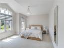 Bedroom featuring multiple windows, light colored carpet, a chandelier, and vaulted ceiling
