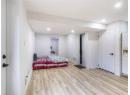 Bedroom with light wood finished floors, white fridge with ice dispenser, and recessed lighting