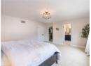 Bedroom featuring light carpet, ensuite bath, and a closet