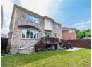 Back of house featuring stairs, a fenced backyard, and brick siding
