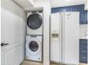 Laundry area featuring stacked washer / dryer and light wood-style flooring