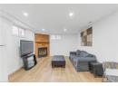 Living room with light wood-style flooring, recessed lighting, and a brick fireplace
