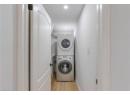 Laundry room with stacked washing machine and dryer, light wood-type flooring, and recessed lighting
