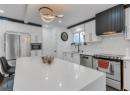Kitchen featuring appliances with stainless steel finishes, backsplash, exhaust hood, light countertops, and white cabinetry