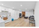 Kitchen with white appliances, a brick fireplace, light wood-style flooring, white cabinetry, and recessed lighting