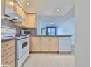 Kitchen featuring white appliances, light brown cabinets, under cabinet range hood, decorative backsplash, and recessed lighting