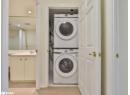 Laundry area featuring stacked washer / drying machine, recessed lighting, and light tile patterned flooring