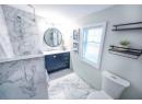 Bathroom featuring vanity, toilet, and a tile shower