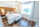 Bedroom with dark hardwood / wood-style flooring, vaulted ceiling, ceiling fan, and wooden walls