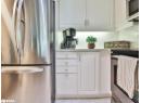 Kitchen featuring stainless steel appliances, white cabinetry, light tile patterned floors, backsplash, and light stone counters
