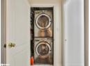 Laundry room with tile patterned flooring and stacked washing machine and dryer