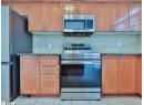 Kitchen featuring stainless steel appliances, dark stone counters, light tile patterned flooring, and brown cabinetry