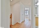 Hall with an upstairs landing, light wood-type flooring, and recessed lighting