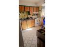 Kitchen with white range with electric stovetop, light floors, under cabinet range hood, brown cabinetry, and freestanding refrigerator