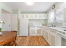 Kitchen featuring white appliances, light wood-type flooring, light countertops, white cabinets, and glass insert cabinets