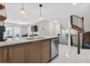 Kitchen with light stone countertops, decorative light fixtures, light tile patterned flooring, stainless steel dishwasher, and open floor plan