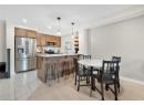 Kitchen with stainless steel appliances, brown cabinets, a peninsula, a breakfast bar, and light stone counters
