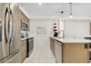 Kitchen featuring stainless steel appliances, tasteful backsplash, brown cabinetry, and light stone counters