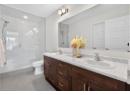 Bathroom featuring a shower stall, light tile patterned floors, and double vanity