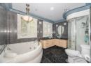 Full bathroom with tile walls, vanity, a tub with jets, a stall shower, and dark marble finish floors