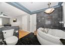Bathroom with tile walls, a garden tub, tile patterned floors, and ceiling fan