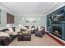 Living area featuring wood finished floors, crown molding, recessed lighting, a lit fireplace, and built in features