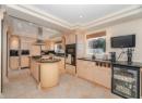 Kitchen featuring a raised ceiling, wine cooler, light brown cabinets, island range hood, and dark stone countertops
