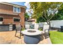 View of patio featuring an outdoor kitchen, a fire pit, and an outbuilding