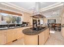 Kitchen featuring island exhaust hood, dark stone countertops, light brown cabinets, hanging light fixtures, and a kitchen island
