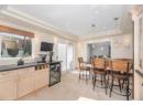Kitchen with a tray ceiling, dark stone counters, wine cooler, pendant lighting, and recessed lighting