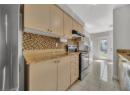 Kitchen with stainless steel appliances, decorative backsplash, light tile patterned floors, and light stone counters