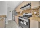 Kitchen featuring appliances with stainless steel finishes, ventilation hood, light stone counters, and light tile patterned floors