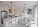 Kitchen featuring appliances with stainless steel finishes, white cabinetry, a breakfast bar area, decorative light fixtures, and light tile patterned floors