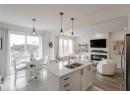 Kitchen featuring light stone countertops, white cabinets, freestanding refrigerator, decorative light fixtures, and open floor plan