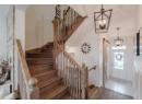 Foyer entrance featuring wood finished floors, a barn door, a chandelier, and stairway