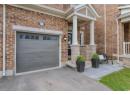 Property entrance with brick siding, a garage, and covered porch
