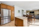 Kitchen with freestanding refrigerator, light tile patterned floors, brown cabinetry, recessed lighting, and light countertops