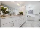 Full bath with double vanity, a marble finish shower, a soaking tub, and light marble finish floors