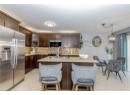 Kitchen with stainless steel appliances, dark brown cabinetry, backsplash, light tile patterned floors, and glass insert cabinets