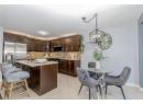 Kitchen featuring decorative backsplash, dark brown cabinets, stainless steel appliances, a kitchen breakfast bar, and light tile patterned flooring