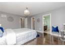 Bedroom with wood finished floors, a chandelier, a textured ceiling, and ensuite bath