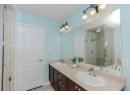 Bathroom with double vanity, a stall shower, light tile patterned floors, a bath, and a chandelier