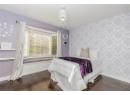 Bedroom with wallpapered walls, dark wood-type flooring, and a textured ceiling