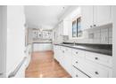 Kitchen with white appliances, dark countertops, decorative backsplash, light wood-style flooring, and white cabinetry