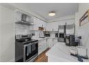 Kitchen featuring appliances with stainless steel finishes, wall chimney exhaust hood, backsplash, and white cabinetry