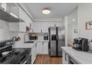 Kitchen with appliances with stainless steel finishes, wall chimney range hood, dark wood-style floors, and white cabinetry