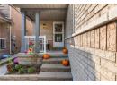 Entrance to property with a porch and brick siding