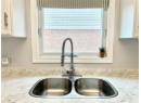 Kitchen view of white cabinetry and light stone counters