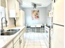 Kitchen featuring white appliances, a ceiling fan, white cabinetry, and light stone counters
