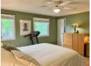 Bedroom with a textured ceiling, wood finished floors, and a ceiling fan